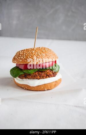 Hamburger végétalien à base de haricots rouges, de poivron rouge, d'épinards et de yaourt blanc. Délicieux hamburger végétarien frais sur une planche à découper. Banque D'Images