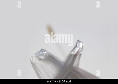 FLOU ARTISTIQUE. Sac en plastique. Poignées de sacs en cellophane. Une lame d'herbe sèche et floue s'accroche. Problèmes écologiques. Gros plan. Concept minimaliste. Hors foyer. Banque D'Images