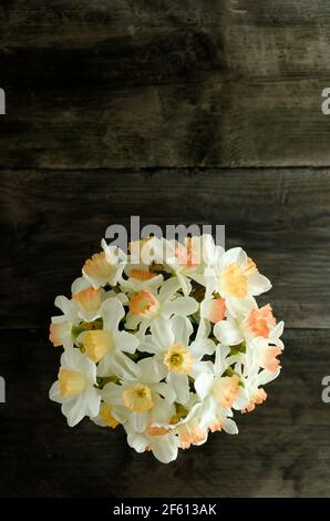 Une vue de dessus d'un bouquet de jaune et orange affodils d'un côté d'une table en bois sombre Banque D'Images