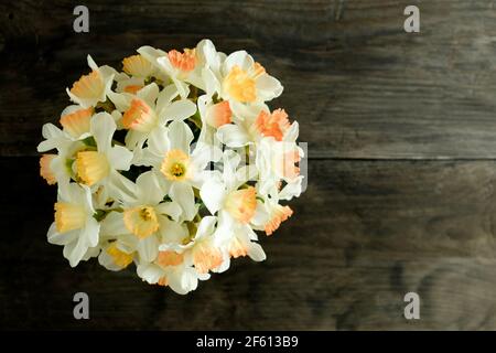 Une vue de dessus d'un bouquet de jaune et orange affodils d'un côté d'une table en bois sombre Banque D'Images