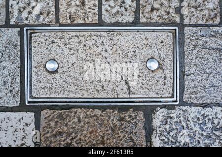 Brique dans un cadre métallique avec deux rivets. Deux goupilles métalliques sont entraînées dans le rectangle en pierre. Arrière-plan, cadre de texture pour le texte. Banque D'Images