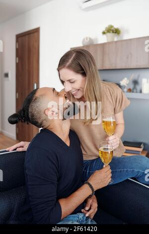Un jeune couple heureux, amoureux, embrasse et boit du champagne quand passer la soirée à la maison Banque D'Images