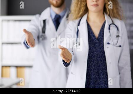 Deux médecins debout et offrant une main d'aide pour secouer la main ou sauver la vie. Aide médicale, lutte contre l'infection virale et le concept de médecine Banque D'Images