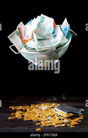 L'argent russe dans un tamis sur fond sombre. Le concept de l'inégalité financière. Banque D'Images
