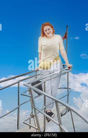 Une jeune femme blanche pose pour photographe sur un arc de yacht touristique. Banque D'Images