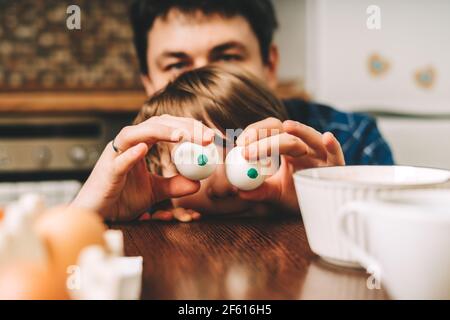 Le jour de Pâques. Père et fils peignant des œufs sur fond de bois. Cuisine familiale. Préparation pour Pâques, décoration maison créative Banque D'Images