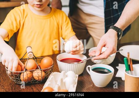 Le jour de Pâques. Père et fils peignant des œufs sur fond de bois. Cuisine familiale. Préparation pour Pâques, décoration maison créative Banque D'Images