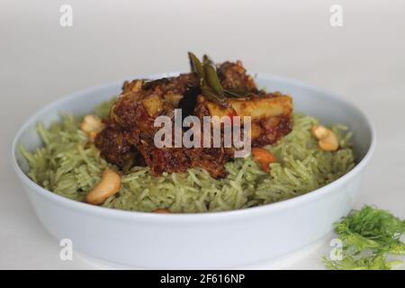 Coriander pulao fait maison, une préparation de riz en une casserole dans le ghee avec des oignons, chutney vert et épices entières. Servi avec du rôti de mouton. Prise de vue sur bac blanc Banque D'Images