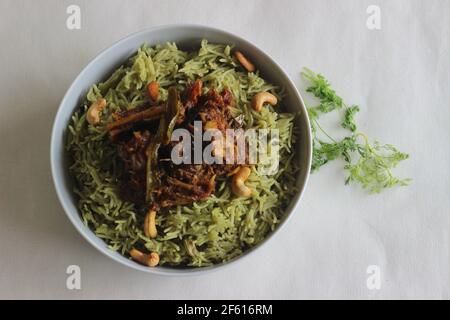 Coriander pulao fait maison, une préparation de riz en une casserole dans le ghee avec des oignons, chutney vert et épices entières. Servi avec du rôti de mouton. Prise de vue sur bac blanc Banque D'Images