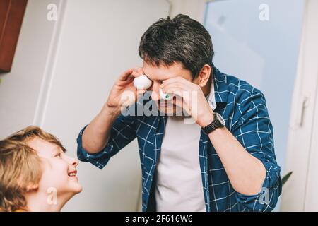 Le jour de Pâques. Père et fils peignant des œufs sur fond de bois. Cuisine familiale. Préparation pour Pâques, décoration maison créative Banque D'Images