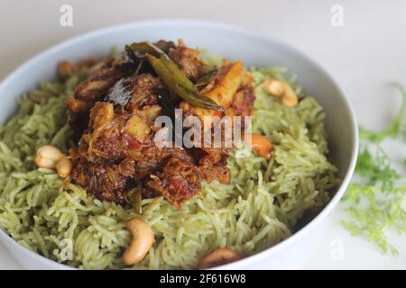 Coriander pulao fait maison, une préparation de riz en une casserole dans le ghee avec des oignons, chutney vert et épices entières. Servi avec du rôti de mouton. Prise de vue sur bac blanc Banque D'Images