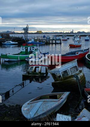 Vue paisible de Paddy’s Hole à Teesport avec les petits bateaux de pêche locaux dans le port et les machines du grand port de fret. Banque D'Images