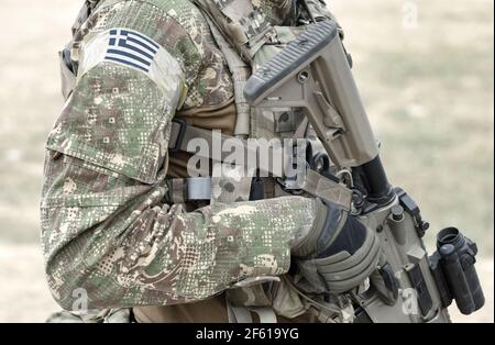 Soldat avec fusil d'assaut et drapeau de la Grèce sur l'uniforme militaire. Collage. Banque D'Images