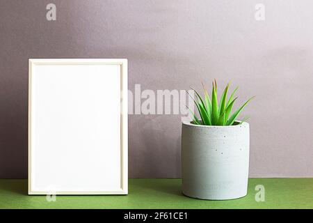 Maquette d'affiche à cadre blanc dans un intérieur minimaliste, installation de maison succulente dans une casserole en béton. Composition en intérieur scandi, couleurs gris-vert. Banque D'Images