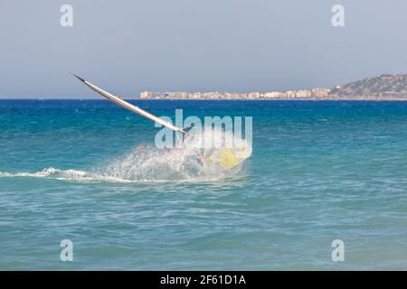 La planche à voile fait des cascades extrêmes sur l'eau, tombe dans la mer, beaucoup d'éclaboussures Banque D'Images