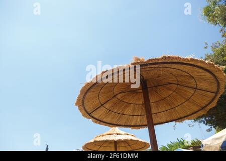 Grands parasols en paille sur la plage contre le ciel Banque D'Images