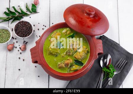 Curry de poulet vert avec ingrédients crus qui est disposé dans un matériel de terre avec fond blanc. Banque D'Images