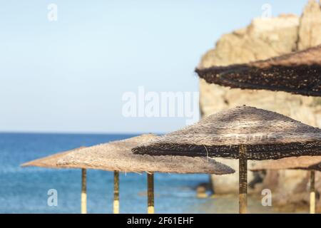Grands parasols en paille sur la plage contre la mer et ciel Banque D'Images
