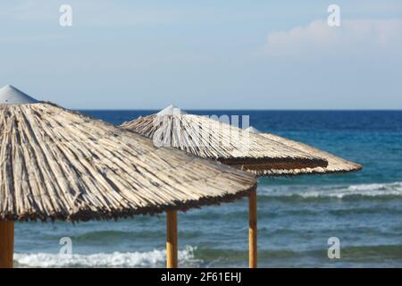 Grands parasols en paille contre la mer et le ciel bleu Banque D'Images