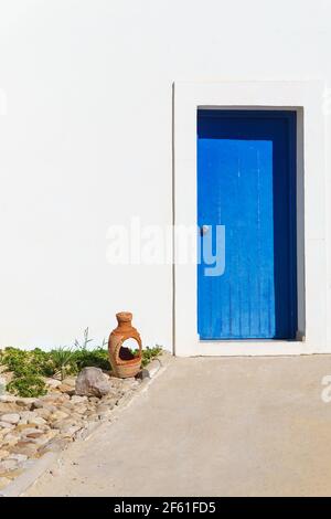 La porte en bois est d'une couleur bleu riche dans un mur blanc. Lumière du soleil de l'après-midi. Un fragment de maison. Copier l'espace. Banque D'Images