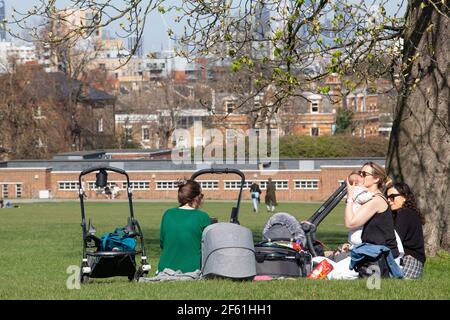 Londres, Royaume-Uni, 29 mars 2021 : à Brockwell Park, dans le sud de Londres, les gens ont profité du temps ensoleillé le premier jour de l'assouplissement du confinement en Angleterre. Certaines personnes s'exerçaient et d'autres piquées en petits groupes. Pour les parents de petits enfants, la possibilité de contacts sociaux est essentielle à leur santé mentale et au développement de leurs enfants. Anna Watson/Alay Live News Banque D'Images