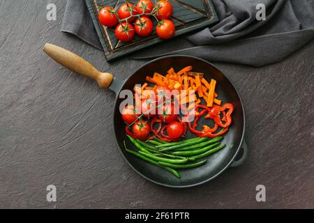 Poêle à frire avec de savoureux légumes sur fond sombre Banque D'Images