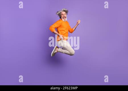 Photo pleine grandeur d'un jeune homme joyeux et branché saut jouant de la guitare invisible isolée sur fond violet Banque D'Images