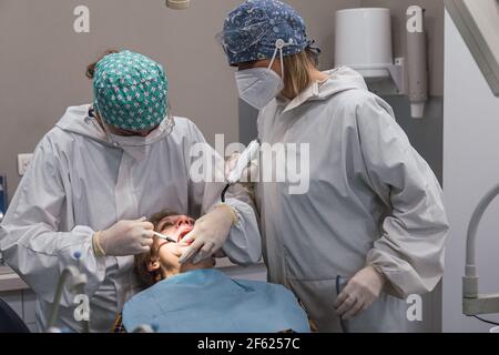 Deux femmes dentistes travaillant avec la bouche ouverte de leur patient. Le dentiste et l'infirmière examinent les dents du patient Banque D'Images