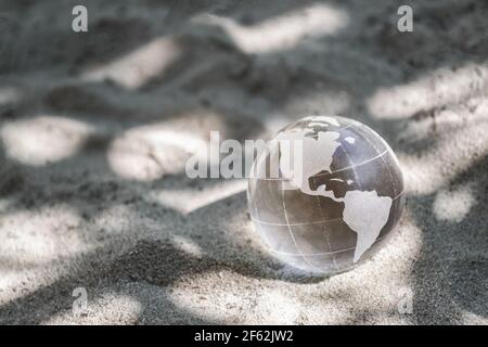Planète de verre sur le sable. Concept de changement climatique, protection de l'environnement. Jour de la Terre Banque D'Images