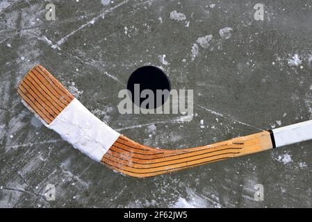 Palet noir et bâton de hockey allongé sur une patinoire. Banque D'Images