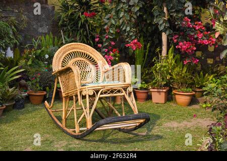 Chaise à bascule, Cane Meubles dans le jardin avec plantes en pot . Banque D'Images