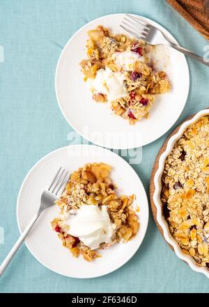 Crumble aux pommes et aux poires avec crème glacée, streusel. Dessert sucré avec une compote de fruits nappée d'un mélange croustillant de crème glacée servie. Deux assiettes avec pomme cobbler. Vue de dessus, verticale Banque D'Images