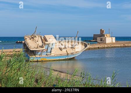 Vieux petit bateau abandonné sur la plage par la côte Banque D'Images