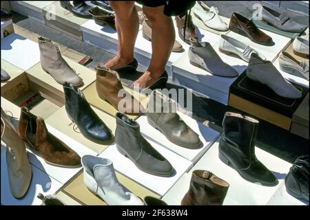 Femme regardant des chaussures exposées sur le sol d'un marché extérieur à Arezzo, Italie. Banque D'Images