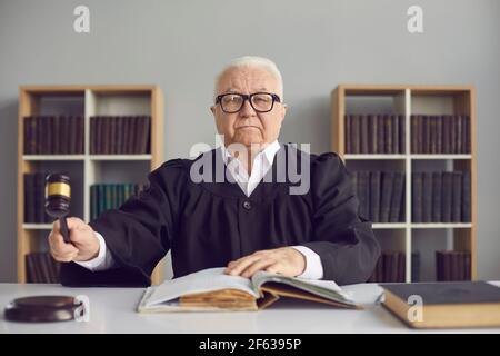 Un juge mûr frappe avec un marteau en passant la phrase et annonce que l'affaire sera close. Banque D'Images