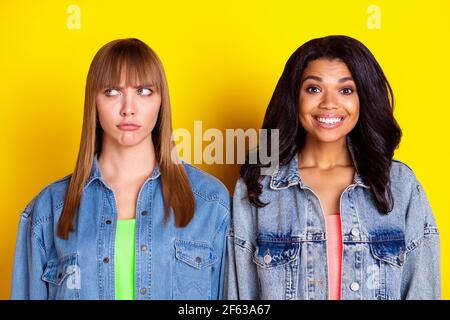 Photo de jeunes filles belles meilleurs amis en colère et souriant femmes ayant un conflit isolé sur fond jaune Banque D'Images