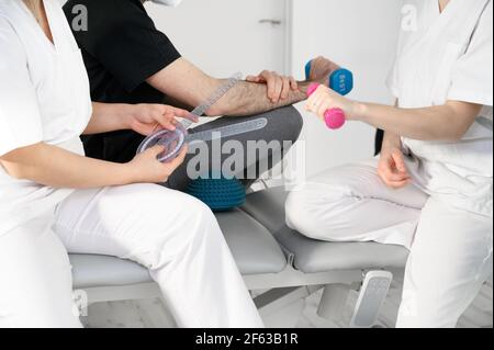 Équipe diversifiée de professionnels de la santé portant un masque facial protecteur, travaillant dans une clinique de réadaptation physique pendant une pandémie de coronavirus. Photo de haute qualité Banque D'Images
