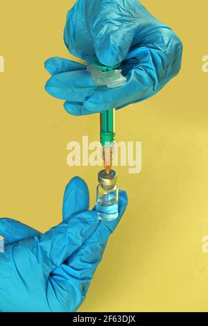 Infirmière portant des gants et tenant le vaccin Covid-19 avec une seringue mains Banque D'Images