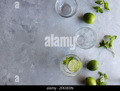 Préparer des cocktails Mojito avec des limes et de la menthe sur la surface grise Banque D'Images