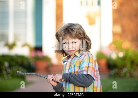 Conflit d'enfants. Agression d'enfant. Concept d'émotion négative. Garçon bouclé en colère avec bâton de danger. Adaptation des enfants. Le concept d'intimidation. La dépression nerveuse. Banque D'Images