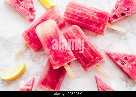 Des pastèques maison avec glace sur fond de marbre blanc. Des pop-sicles de pastèque surgelée. Concept d'été. Vue de dessus. Banque D'Images