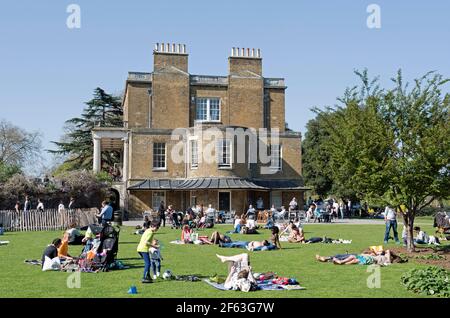 Les gens qui se trouvent sur l'herbe sous le soleil, à côté de la maison Clissode, parc Clissode Stoke Newington Banque D'Images