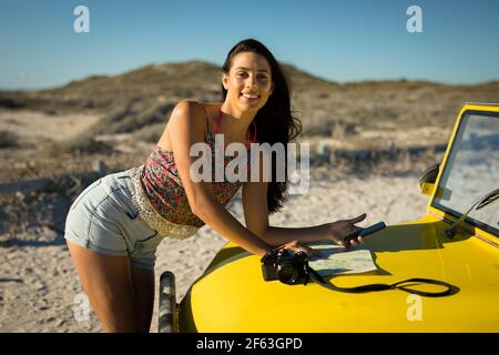 Bonne femme caucasienne s'est penchée contre le buggy de plage au bord de la mer lecture de la feuille de route Banque D'Images