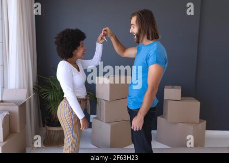 Heureux couple divers déménagement maison souriant et tenant la clé Banque D'Images