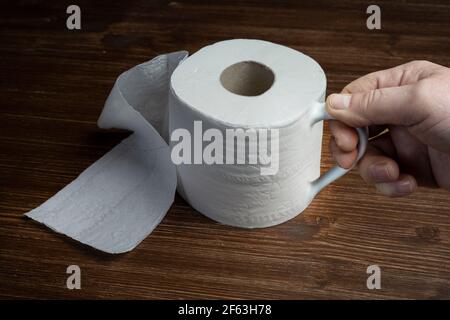 Un rouleau de papier toilette utilisé comme une tasse sur une table en bois Banque D'Images