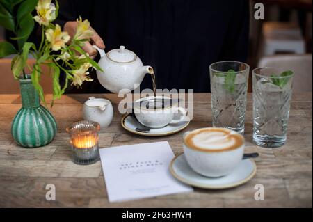 Une femme verse du thé à la main dans une théière au restaurant. Style de vie, concept de thé de l'après-midi. Menu papier vierge avec espace de copie. Londres, Royaume-Uni Banque D'Images