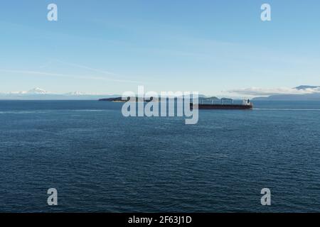 Vue du navire à conteneurs sur un autre navire de cargaison avec la montagne couverte de neige en arrière-plan à l'approche de Vancouver, en Colombie-Britannique. Banque D'Images