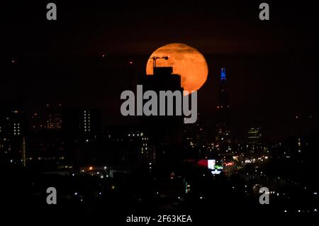 Londres, Royaume-Uni. 29 mars 2021. Une lune gibboteuse de 99 % s'élève au-dessus du centre de Londres. La pleine lune de ce mois-ci est connue sous le nom de Lune des vers, selon l’Almanac de l’ancien agriculteur, reconnaissant que les vers de terre apparaissent alors que le sol se réchauffe au printemps. En outre, c'est une pleine Lune Pascal, étant la première pleine Lune à se produire après l'équinoxe de printemps, ainsi qu'une super lune. Credit: Stephen Chung / Alamy Live News Banque D'Images