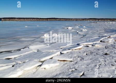 La glace en feuilles flotte dans l'anse partiellement gelée de Rafuses Cove, en Nouvelle-Écosse, au Canada. Un quai protège le port. Banque D'Images