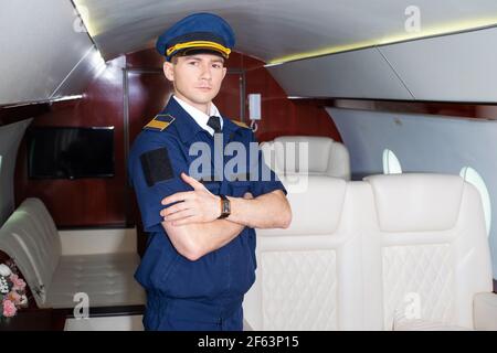 Pilote à bord de l'avion, la cabine d'un avion privé, volant avec confort. Jeune homme en casquette, membre d'équipage. Banque D'Images